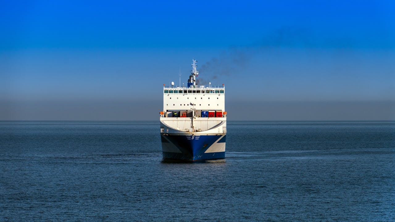 services-06 A large cargo vessel travels across the ocean under a clear blue sky.