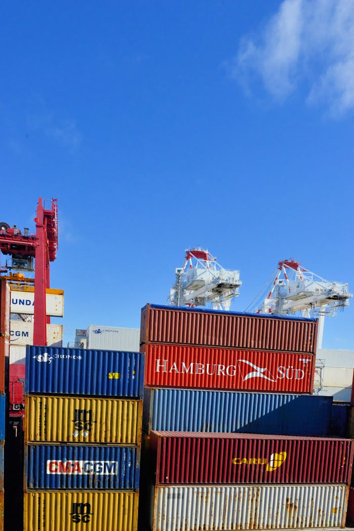 why-choose-us Colorful cargo containers stacked at a busy shipping port under a clear blue sky.