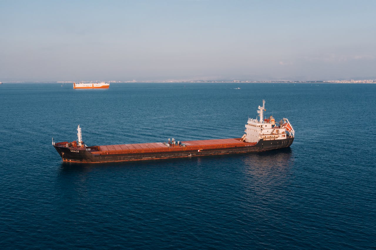 home-hero Aerial view of a cargo ship sailing in the open sea under clear skies, showcasing maritime transport.