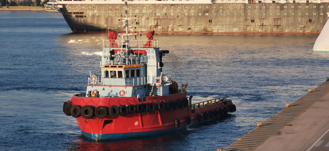 services-03 Tugboat in Athens Harbor assisting cargo ships in golden light. Maritime industry scene.